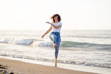 Fototapeta na wymiar Horizontal portrait of woman splashing water in the beach sea. Happiness summer lifestyle concept.