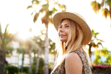 Portrait of a young blonde in a hat on a tropical background. Sunny light and bright colors.