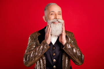 Photo of positive happy old man touch beard magician entertainer smile isolated on red color...
