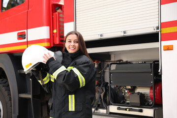 Portrait of firefighter in uniform with helmet near fire truck