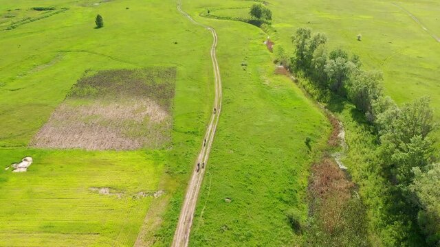 drone footage of a few people biking in the field. opening video