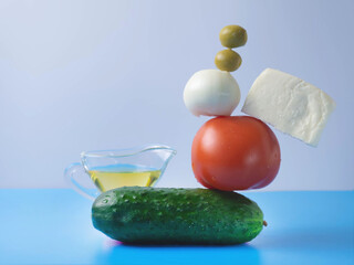 Fresh vegetables fly into the salad on a blue-and-white background. Tomato, cucumber.basil, onion. Creative salad. The concept of healthy food. Balance.