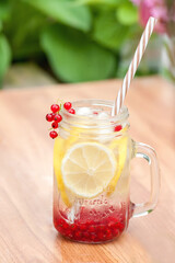 Summer cool drink to quench thirst from lemon and currant with ice cubes on the table in the...