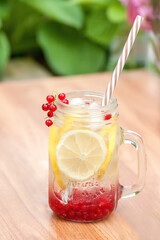 Summer cool drink to quench thirst from lemon and currant with ice cubes on the table in the garden. Summer background 