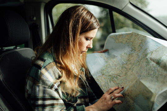 Driver Writing On Paper Map In Car During Trip