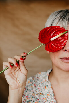 Crop woman covering face with anthurium