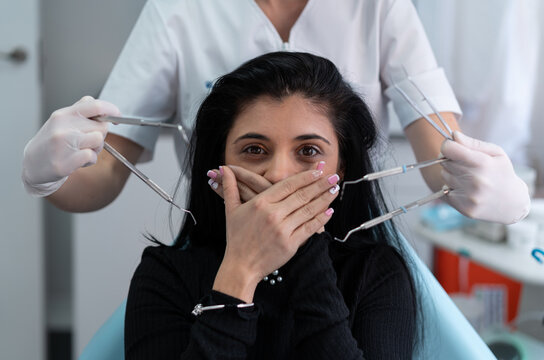 Scared patient covering mouth with hands from dentist