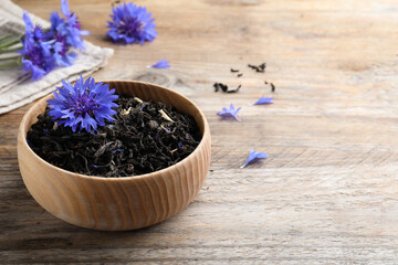 Dried cornflower tea and fresh flowers on wooden table. Space for text