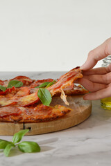 Cropped hand picking up a slice of pepperoni pizza 