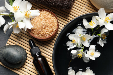 Beautiful spa composition with jasmine essential oil and fresh flowers on table, flat lay