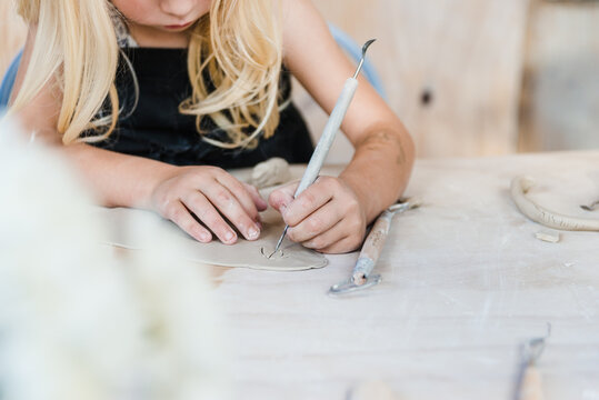Unrecognizable kid cutting clay piece in studio