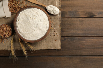 Flat lay composition with wheat flour on wooden table. Space for text