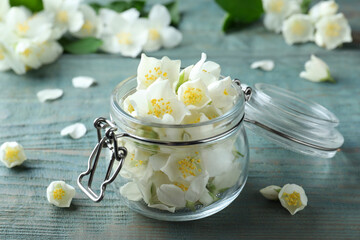 Beautiful jasmine flowers in glass jar on blue wooden table