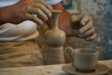 Pottery workshop hands work with clay. A man makes a vase of liquid clay with his hands. Ceramic vase and cup manufacturing process. Do it yourself master class. Place for your text.