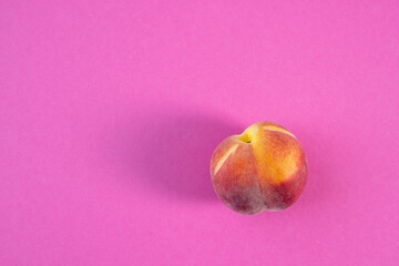 ripe peach lies on a pink background