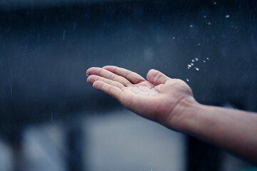 Hand of man catching raindrops.