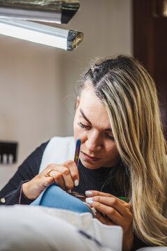Beautician applying eyelashes on face of black woman