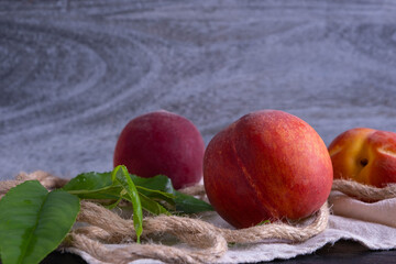 juicy and ripe peaches and green foliage lie on a napkin
