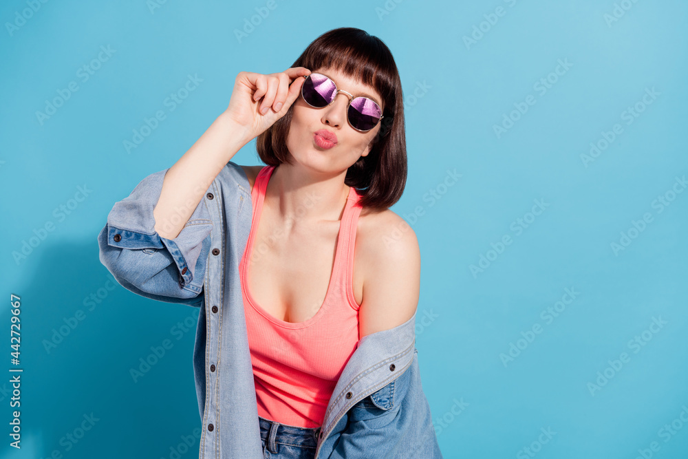 Sticker Portrait of attractive girl sending you air kiss posing touching specs good mood isolated over bright blue color background