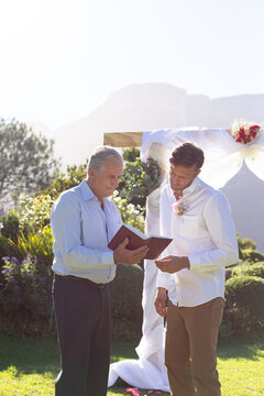 Caucasian groom getting married and talking with wedding officiant
