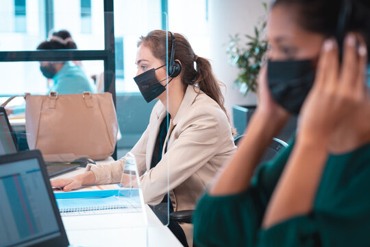 Group of diverse businesspeople wearing face mask using computer