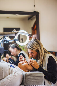 Cosmetologist with black woman during eyelash extension procedure