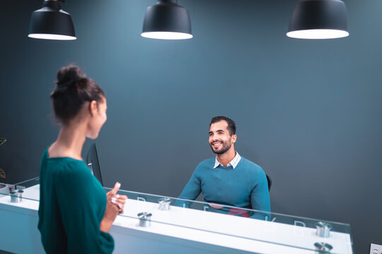 Two diverse businesspeople smiling and sitting at glass table at reception
