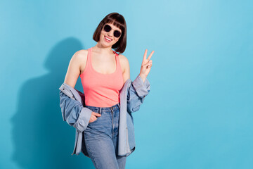 Portrait of attractive cheerful girl showing v-sign copy empty space isolated over bright blue color background