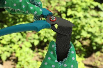 Person sharpening pruner outdoors, closeup. Gardening tools