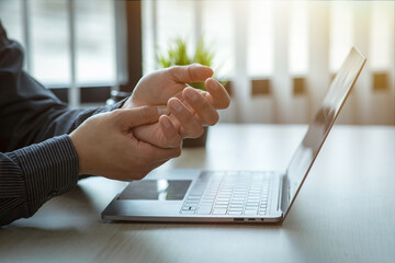 Business man pain in hands while working with laptop. Office syndrome concept.