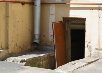 Broken open brown door to the basement of an apartment building