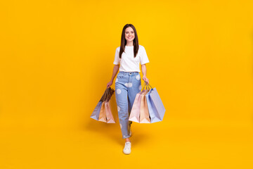 Full size photo of happy smiling beautiful cheerful girl go shopping shopaholic isolated on yellow color background