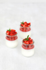 Italian dessert panna cotta with fruit jelly and fresh pieces of strawberries on white background....