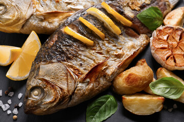 Tasty homemade roasted crucian carps served on slate plate, closeup. River fish