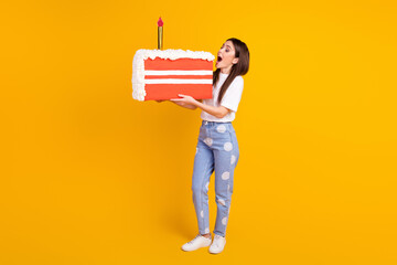 Full size profile side photo of young excited woman bite cake birthday party isolated over yellow...