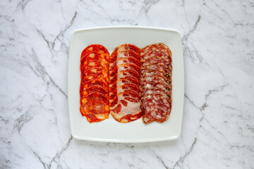 Portuguese sliced meat: copita, salami and Garvao chorizo. Different pork meat on white plate on...