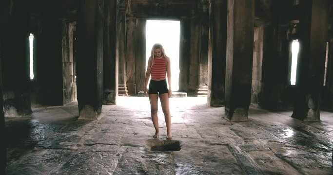 A Wide Shot of Blonde Female Model Dancing Barefoot Inside a  Cambodian Temple 