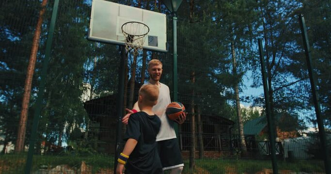 American basketball. Male instructor train little sports boy basketball player outdoors