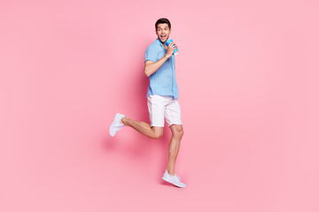 Fototapeta na wymiar Photo of funky man run hold cup enjoy fizzy drink look back empty space wear blue shirt isolated on pink color background