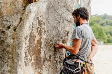 Young caucasian man with a beard climbing takes out magnesium from his bag. risk sport and outdoor activity.
