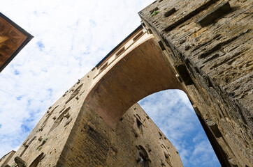 Fototapeta premium Bottom view of a tall ancient arch and blue sky with clouds