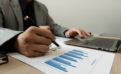 Businessman pointing at graph and chart to analysis use for plans to improve quality, business finances and accounting concept