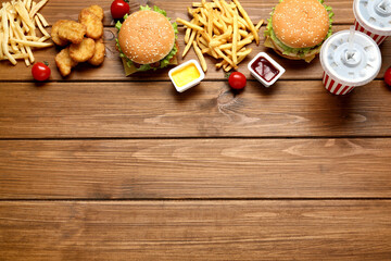 Flat lay composition with delicious fast food menu on wooden table. Space for text