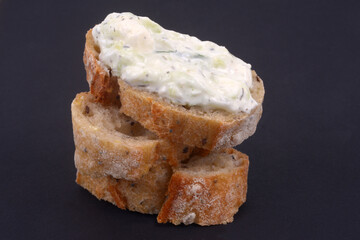 Tartine de tzatziki en gros plan sur fond noir