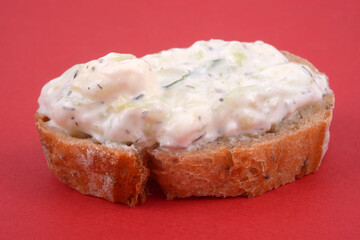 Tartine de tzatziki en gros plan sur fond rouge