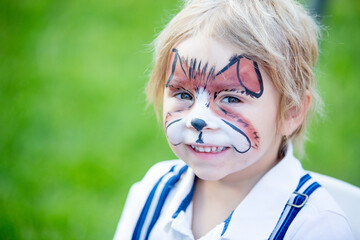 Little toddler baby boy, child with painted face as a dog, playing with pet dog in the garden