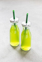 Summer refreshing drink made of gooseberries in a glass bottle with a lid and a straw on a light background