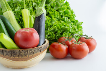 assortment of vegetables in a wooden bowl and next to it on a white background