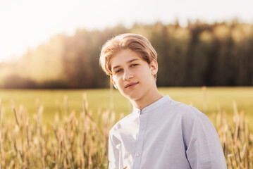 Portrait of a beautiful of millennial boy in nature in the summer. A look at the camera © Olya Komarova