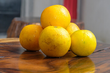 Stack of fresh baby oranges on wooden table. All things yellow.